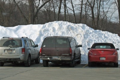 Snow towers over cars in the Southborough commuter rail parking lot
